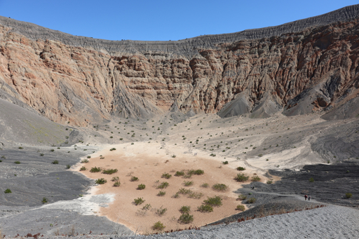Looking across the lower crater area with steep walls surrounding it. Interesting how different areas of the crater have very different color schemes to them, from a rich deep gray to a lighter one as well as various shades of orange. The central orange area looks like sand from a distance, but appears more like cracked clay up close.